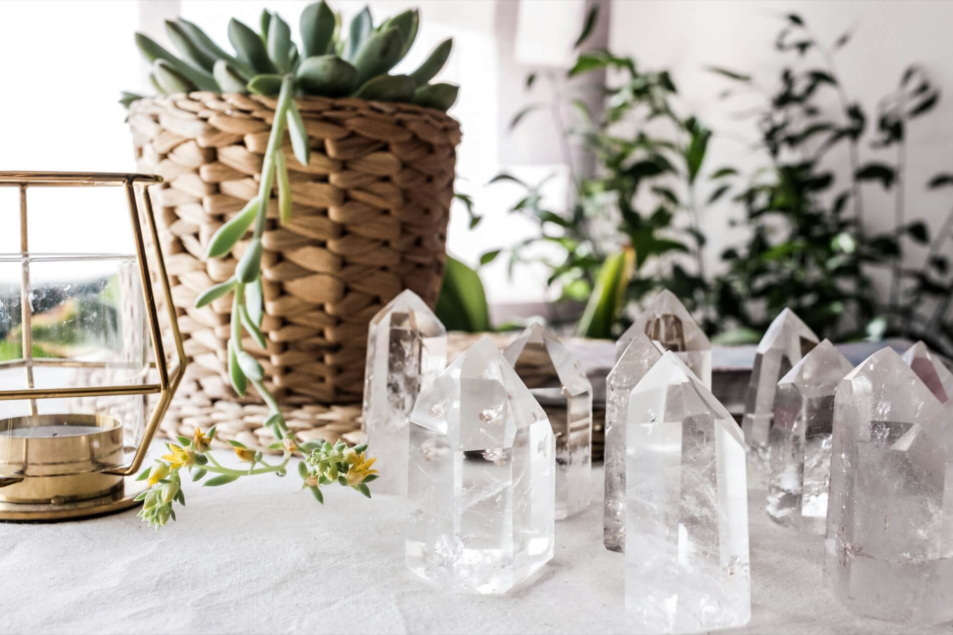 Clear quartz crystal towers groups on a window sill in front of a collection of green houseplants