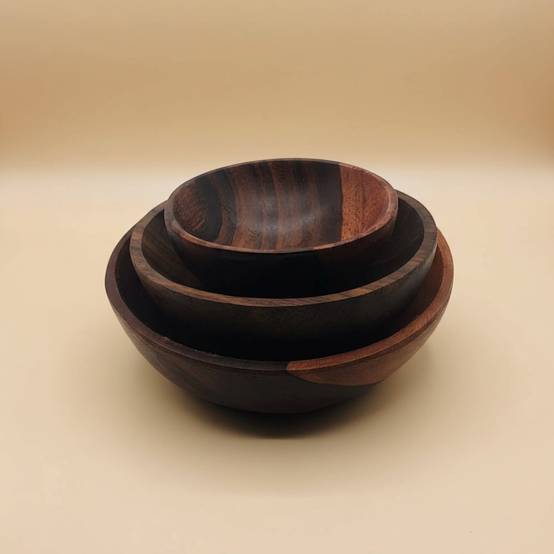 Three Indian Rose Wood bowls of different sizes on a beige background