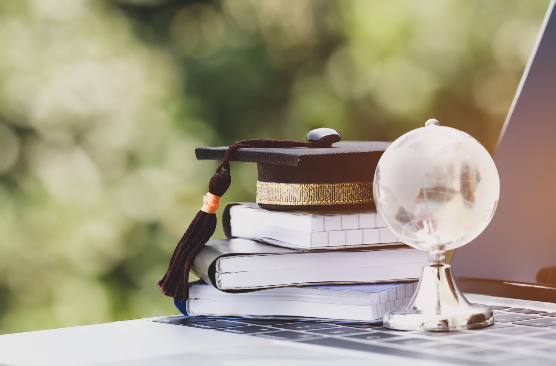 A crystal sphere in a mineral display holder by some books and a university cap
