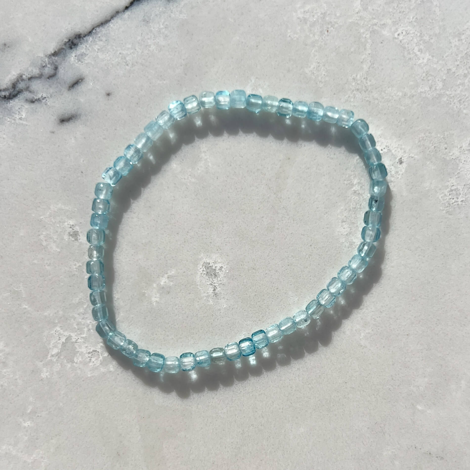 Blue beaded bracelet on a gray marble surface