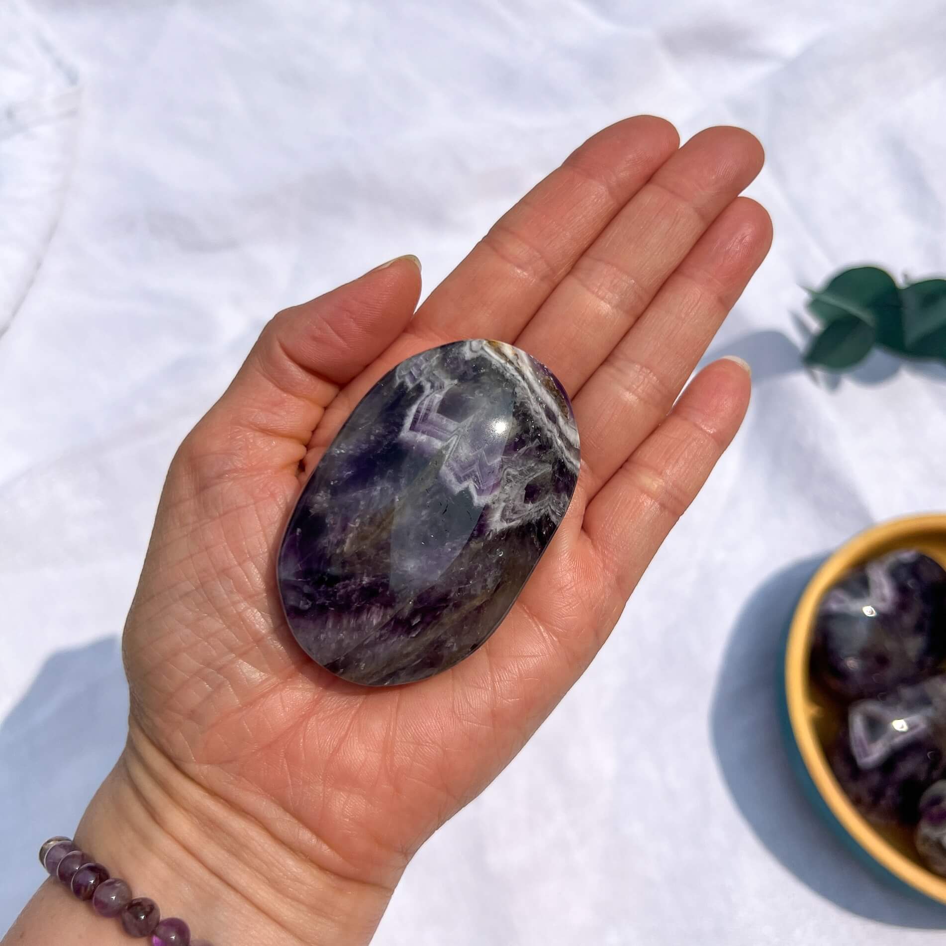 Hand holding a purple and white chevron amethyst crystal with a white background