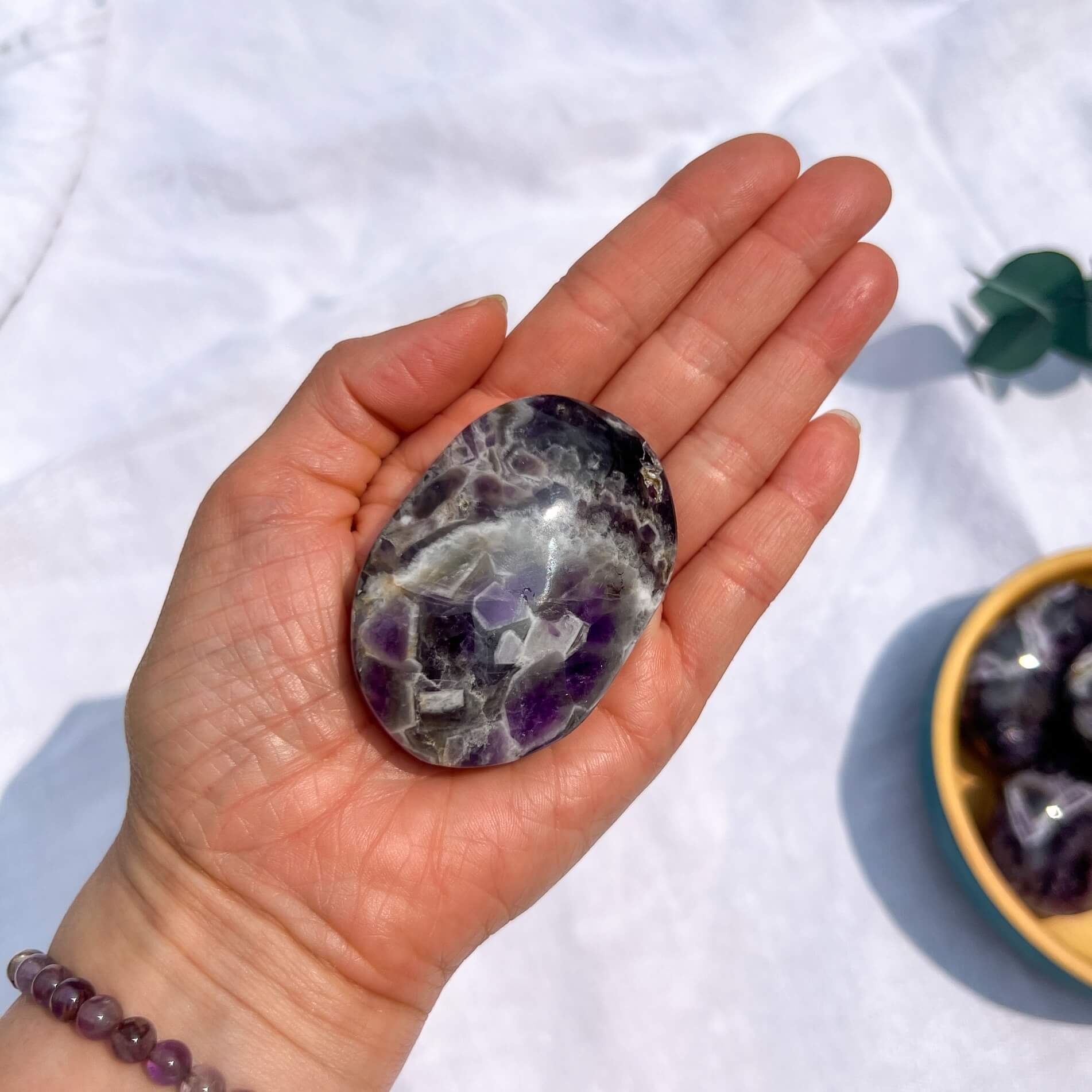 Hand holding a purple and white chevron amethyst crystal with a white background