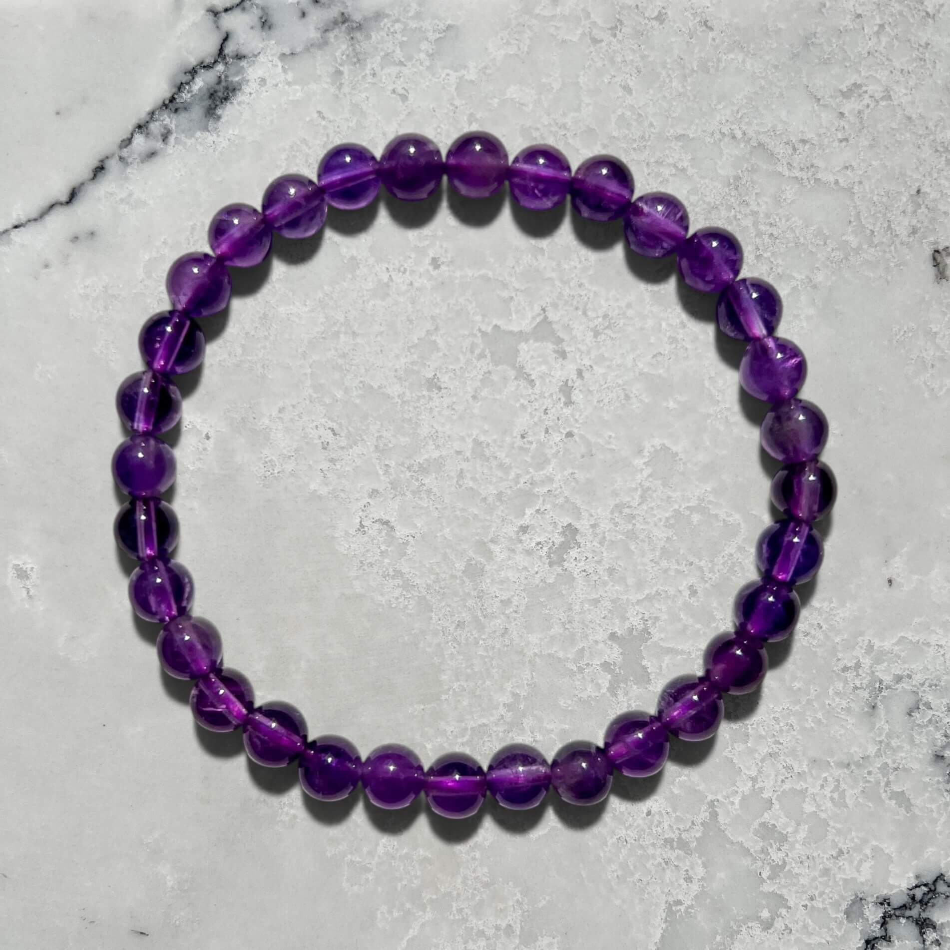 Purple Amethyst bead bracelet on a marble surface