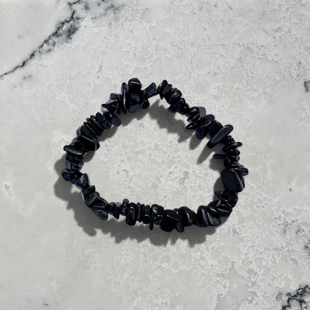 Rock + Realm Crystals black shungite chip bracelet with irregular stone pieces against a natural grey and white marble surface