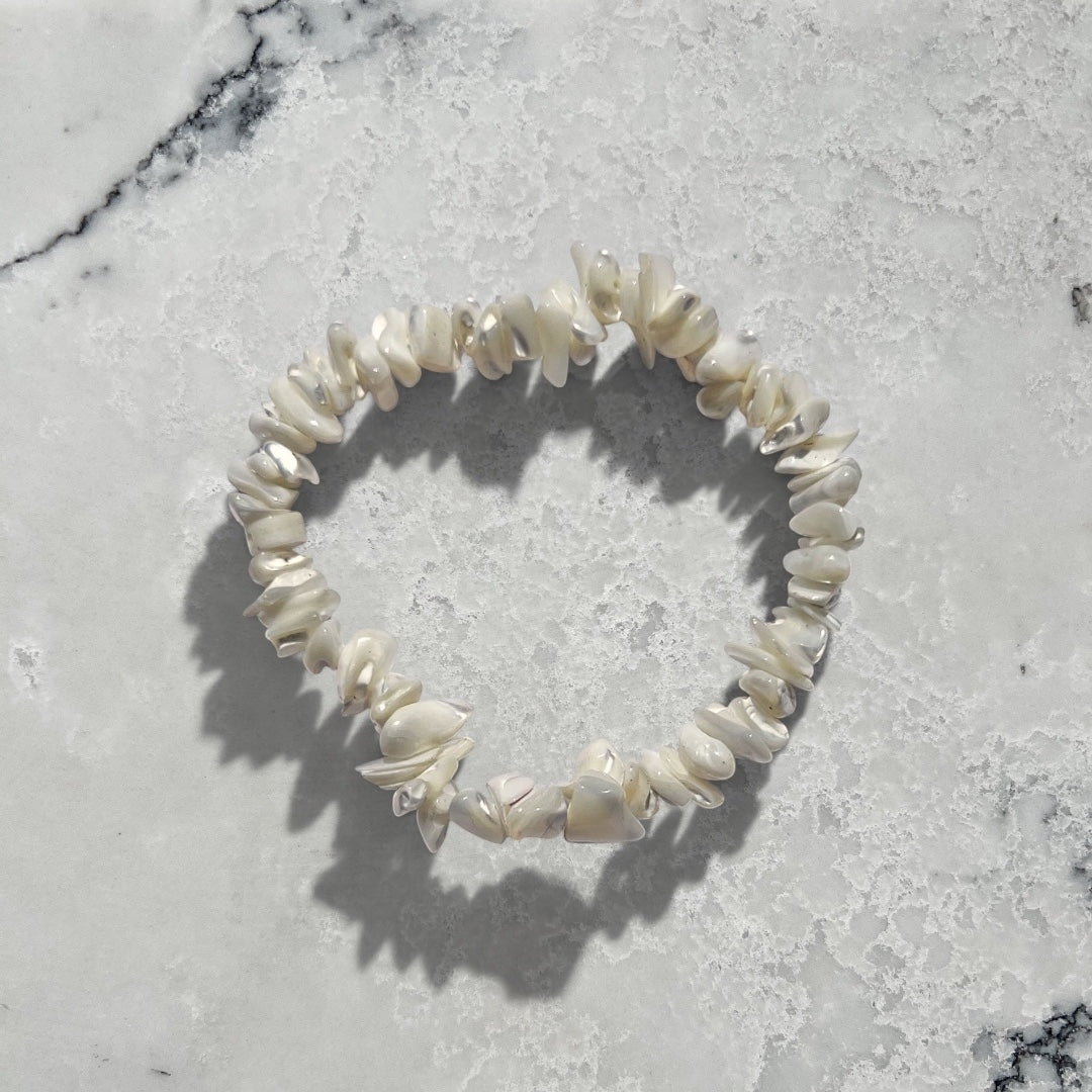Rock + Realm Crystals white mother of pearl chip bracelet with iridescent sheen against a natural white and grey textured marble