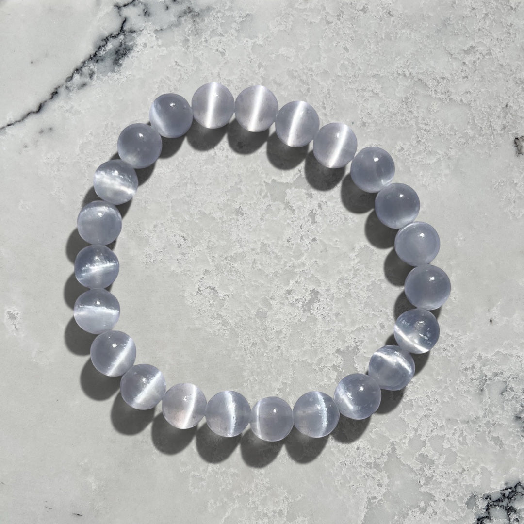 Rock + Realm Crystals large selenite beaded bracelet with a cat's eye effect on a white and grey marble surface