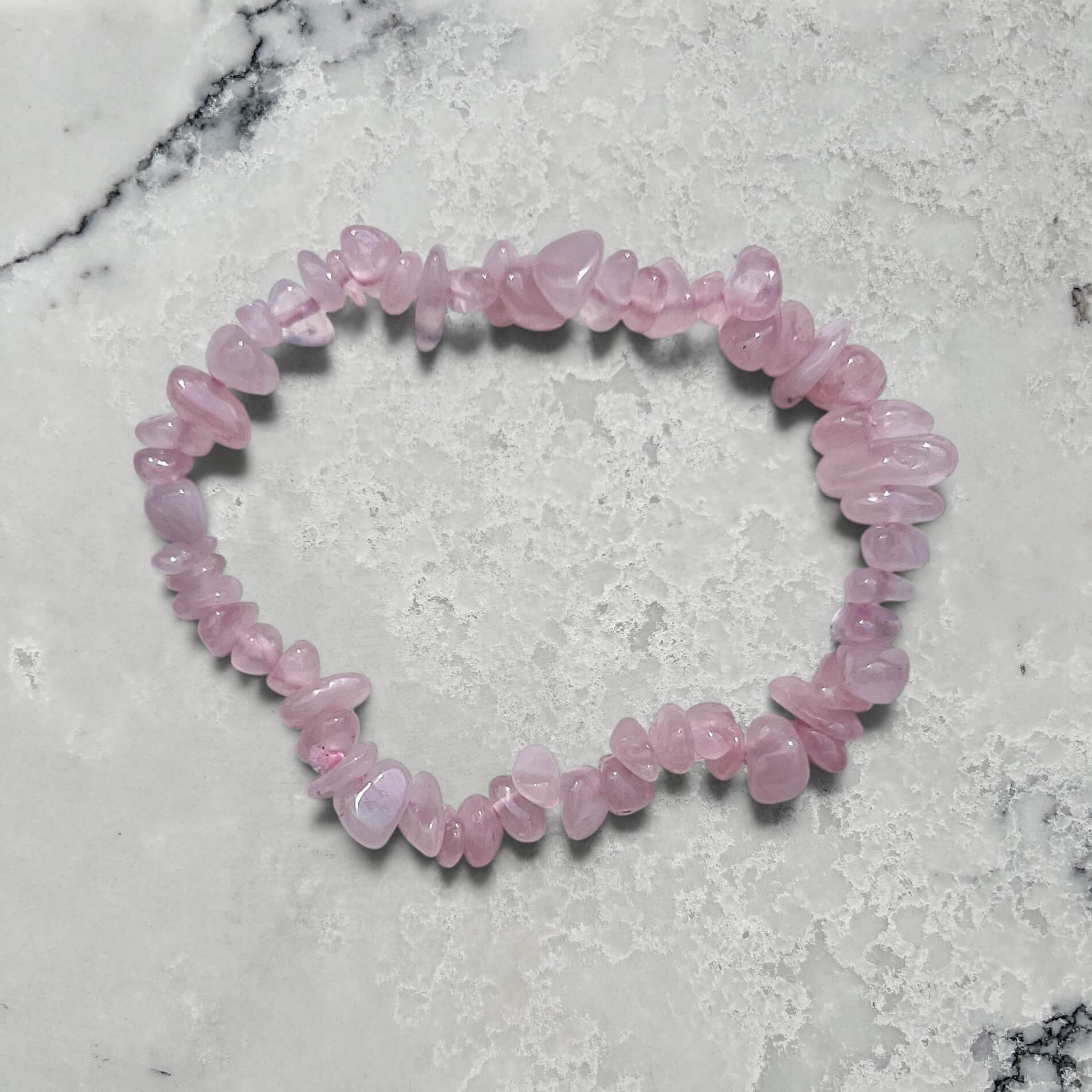 rose quartz crystal chip bracelet on a marble surface