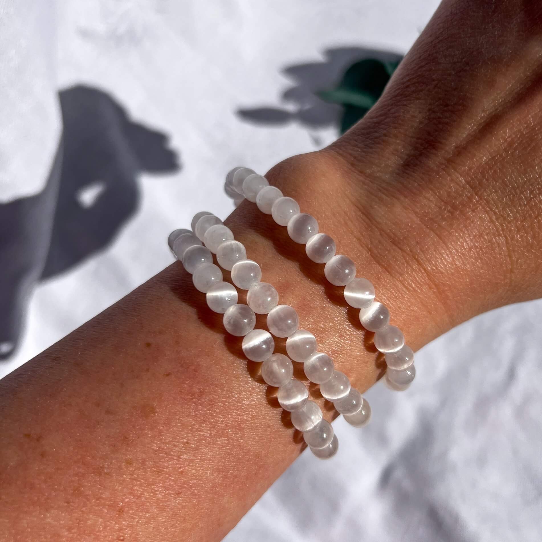 A woman's wrist wearing a shimmering white selenite crystal bead bracelet.