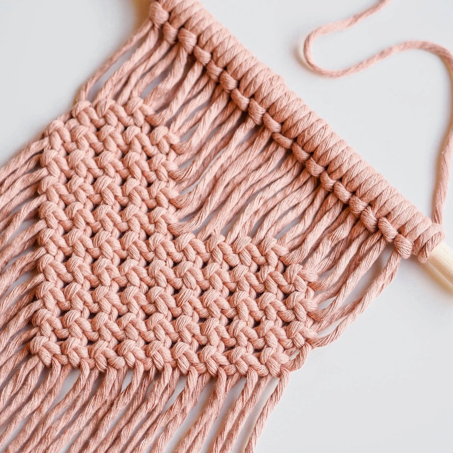 Rose quartz pink Close up of DIY macrame heart wall hanger laid flat