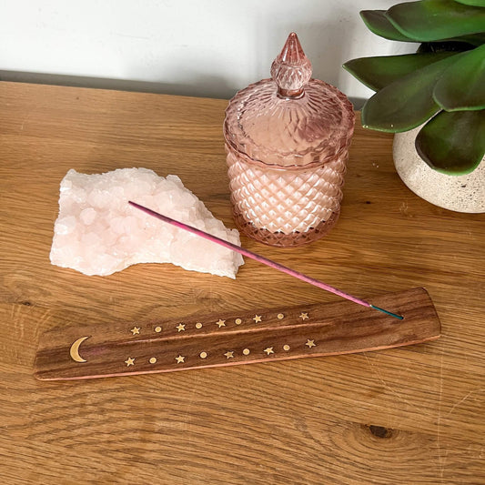 Mango wood ski incense holder with moon and star brass inlaid shown holding a pink incense stick with crystal and pink glass candle holder