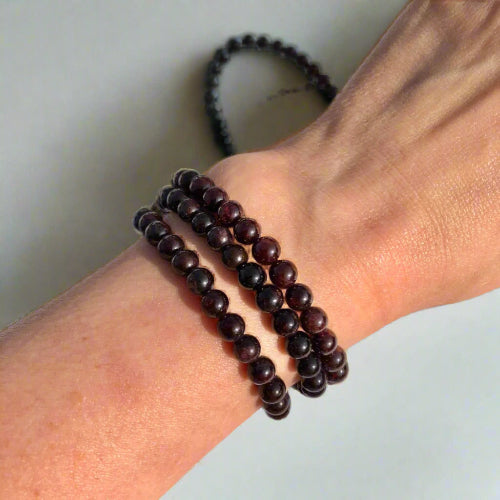 dark red garnet healing crystal bead bracelets worn on a slender wrist
