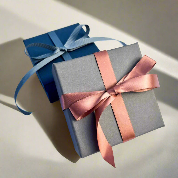 Luxury grey gift box tied in a rose gold pink ribbon with a blue gift box in the background