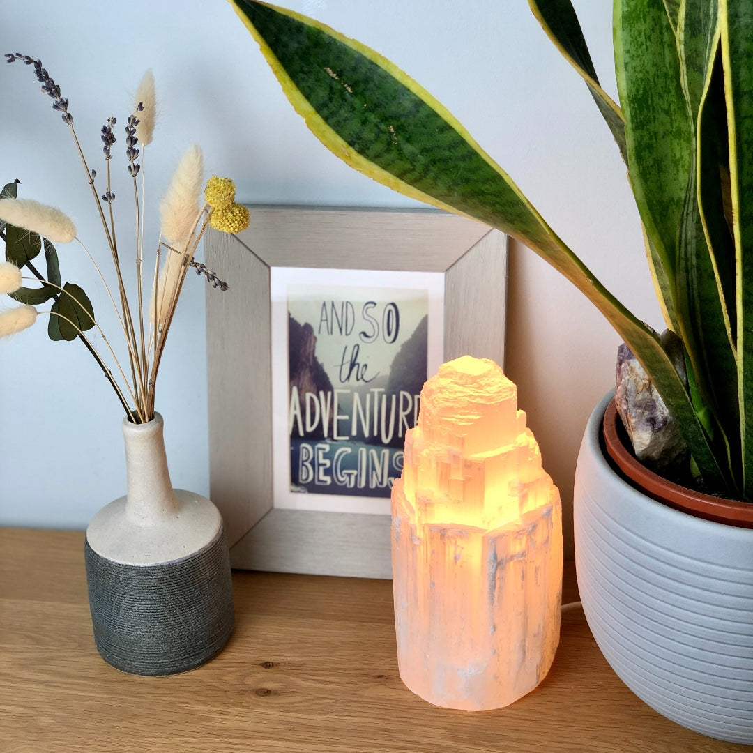 Selenite crystal lamp glowing on a bedside table with ornaments