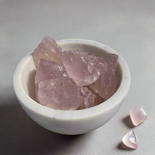 A white marble bowl of gemmy pink rose quartz crystal chunks