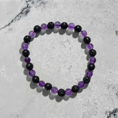 Black lava and purple amethyst crystal bead bracelet on a marble surface