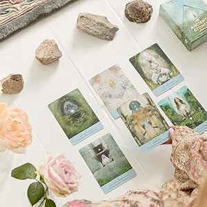 Set of ancient stones oracle cards with nature-themed designs on a surface with rocks and flowers.