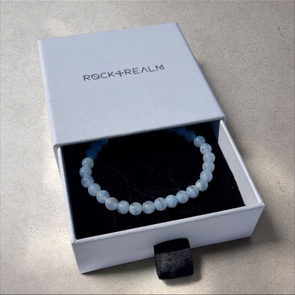 Blue Lace Agate crystal bead Bracelet in a 'Rock + Realm' box on a grey stone background