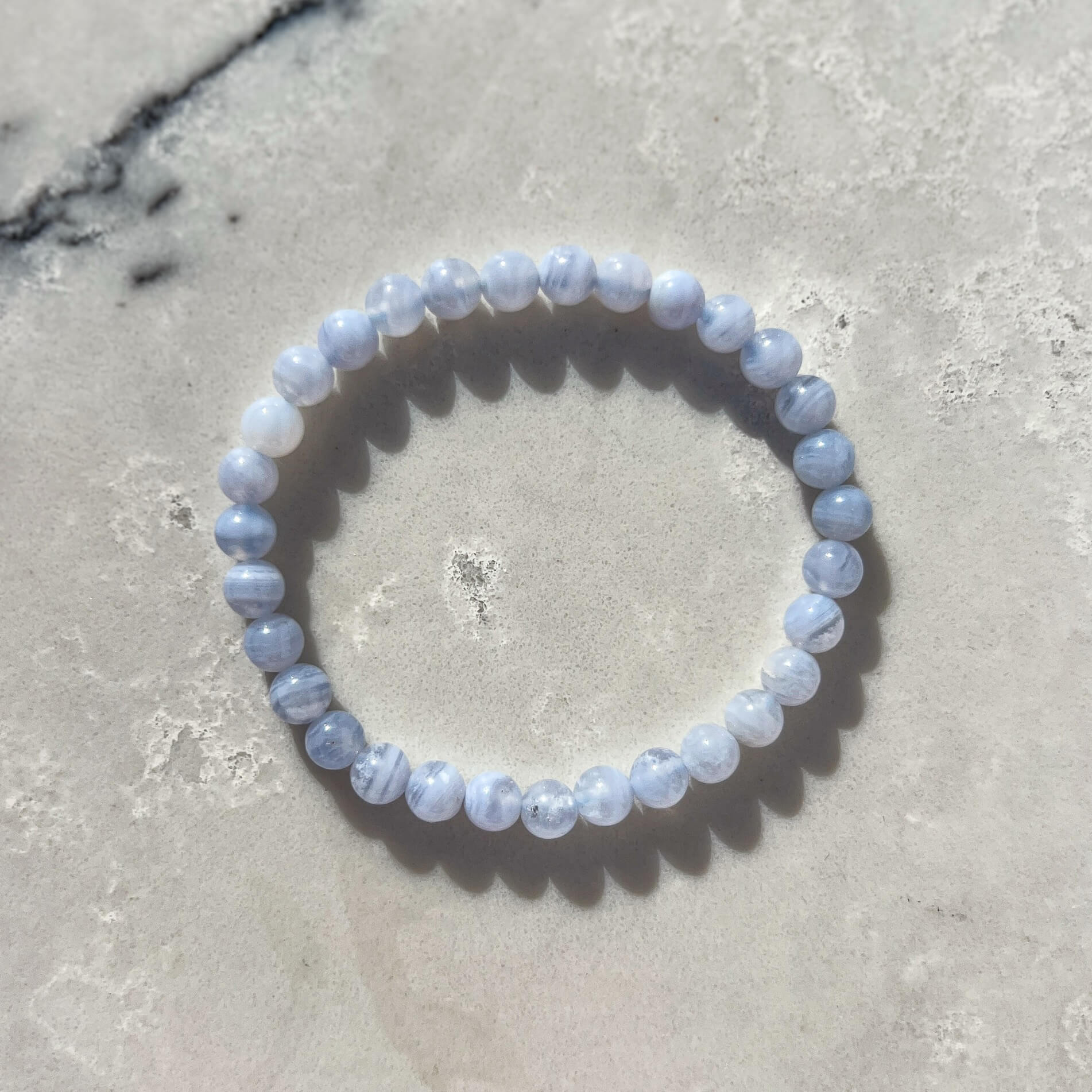 Blue Lace Agate crystal bead bracelet on a textured marble surface