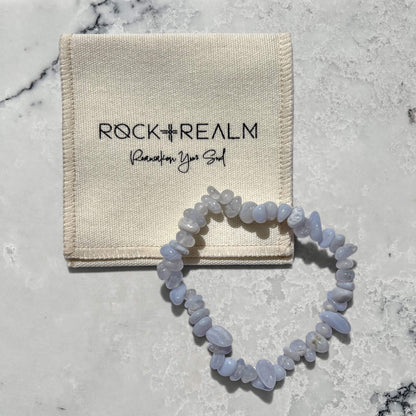 Blue Agate crystal chip gemstone bracelet on a marble surface with cream cotton 'Rock + Realm' pouch.