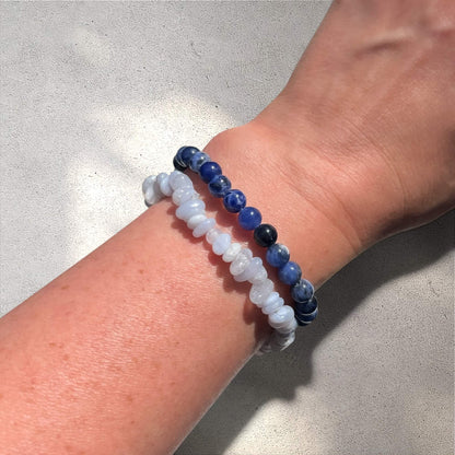 Stack of two Blue Agate crystal chip gemstone and sodalite crystal bead bracelets on a wrist against a neutral background