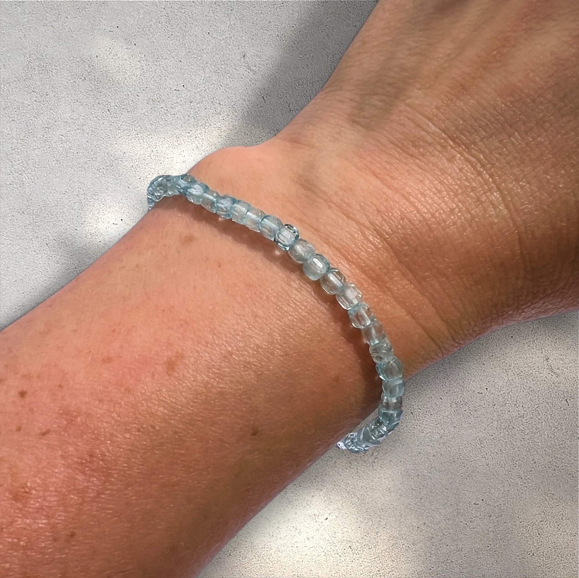 Blue Topaz beaded bracelet on a wrist against a neutral background
