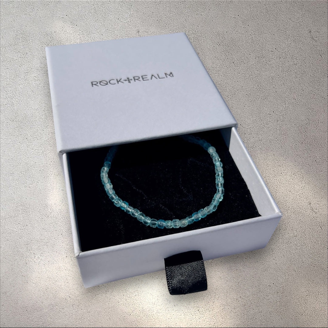 Blue Topaz crystal cube beaded bracelet in a 'Rock+Realm' box on a white fabric background