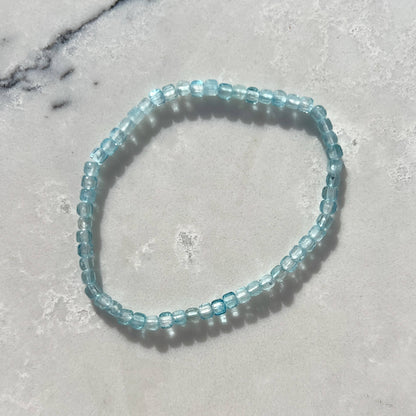 Blue beaded bracelet on a gray marble surface