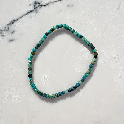 Beaded bracelet with green and teal chrysocolla gemstones on a marble surface