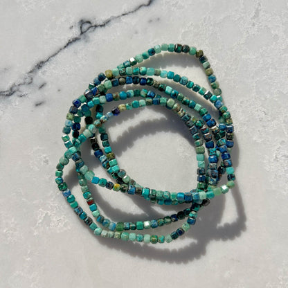 Stack of Chrysocolla crystal Bead bracelets with green and blue stones on a marble surface