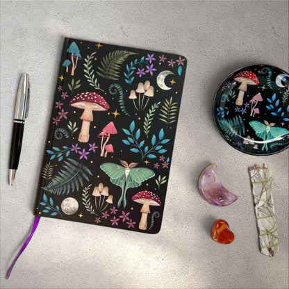 Rock + Realm Crystals Dark Forest A5 notebook with moon, mushrooms, ferns, and luna moth illustration on black cover.