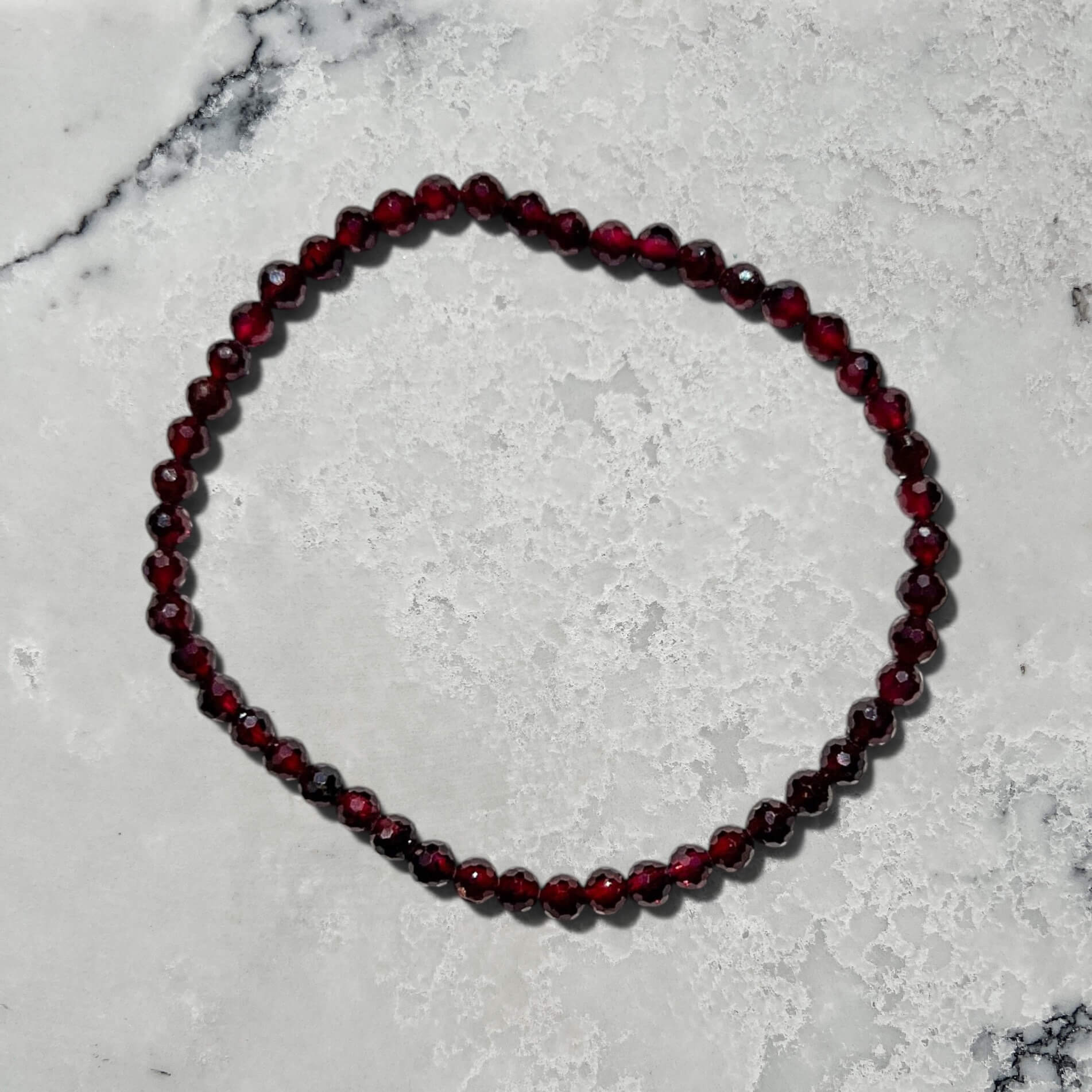 Faceted Garnet crystal bead bracelet on a marble surface