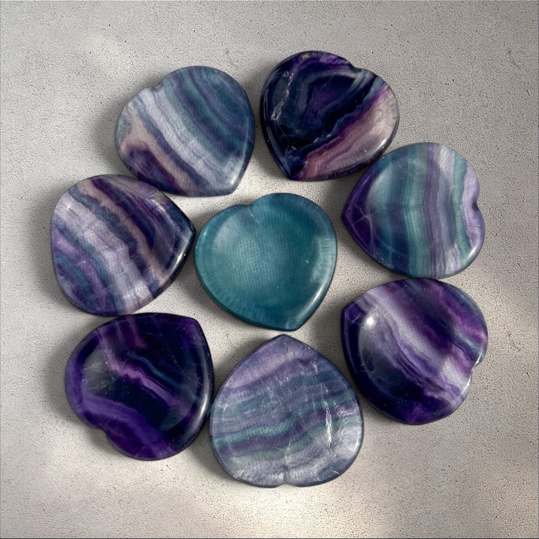 Rock + Realm Crystals blue and purple fluorite heart-shaped worry stones with unique banding. One stone is a solid teal blue.