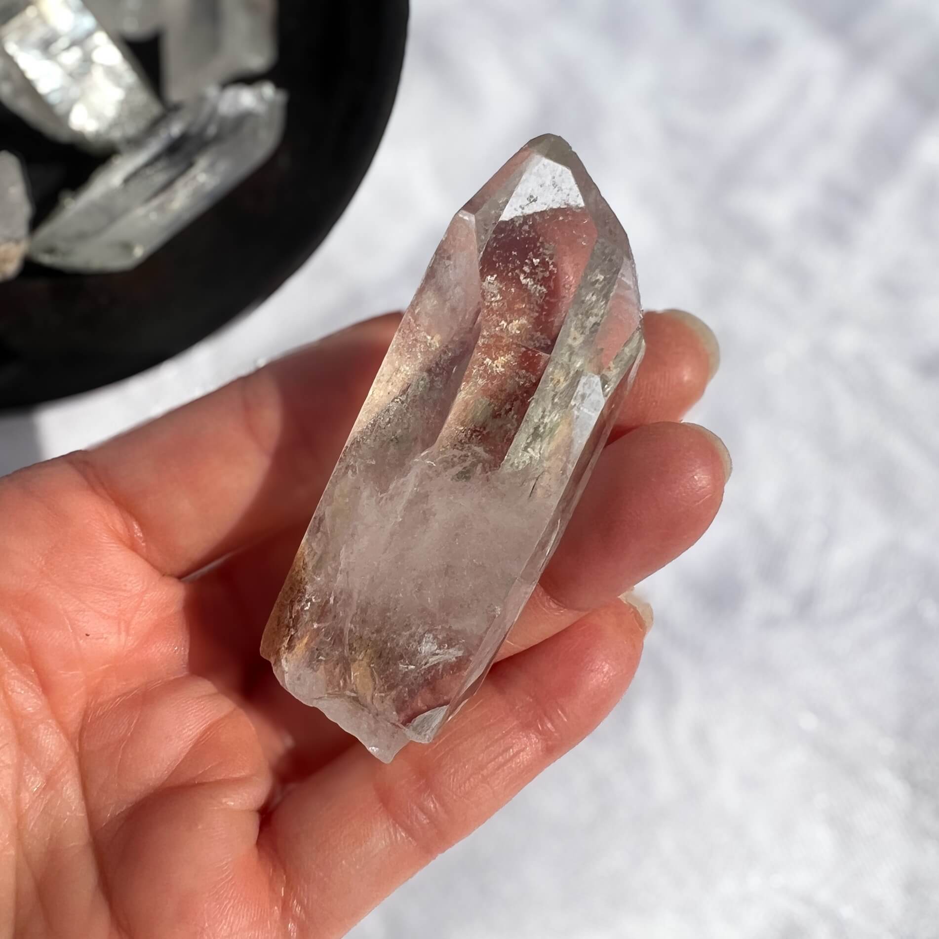 Hand holding a clear crystal with a blurred background