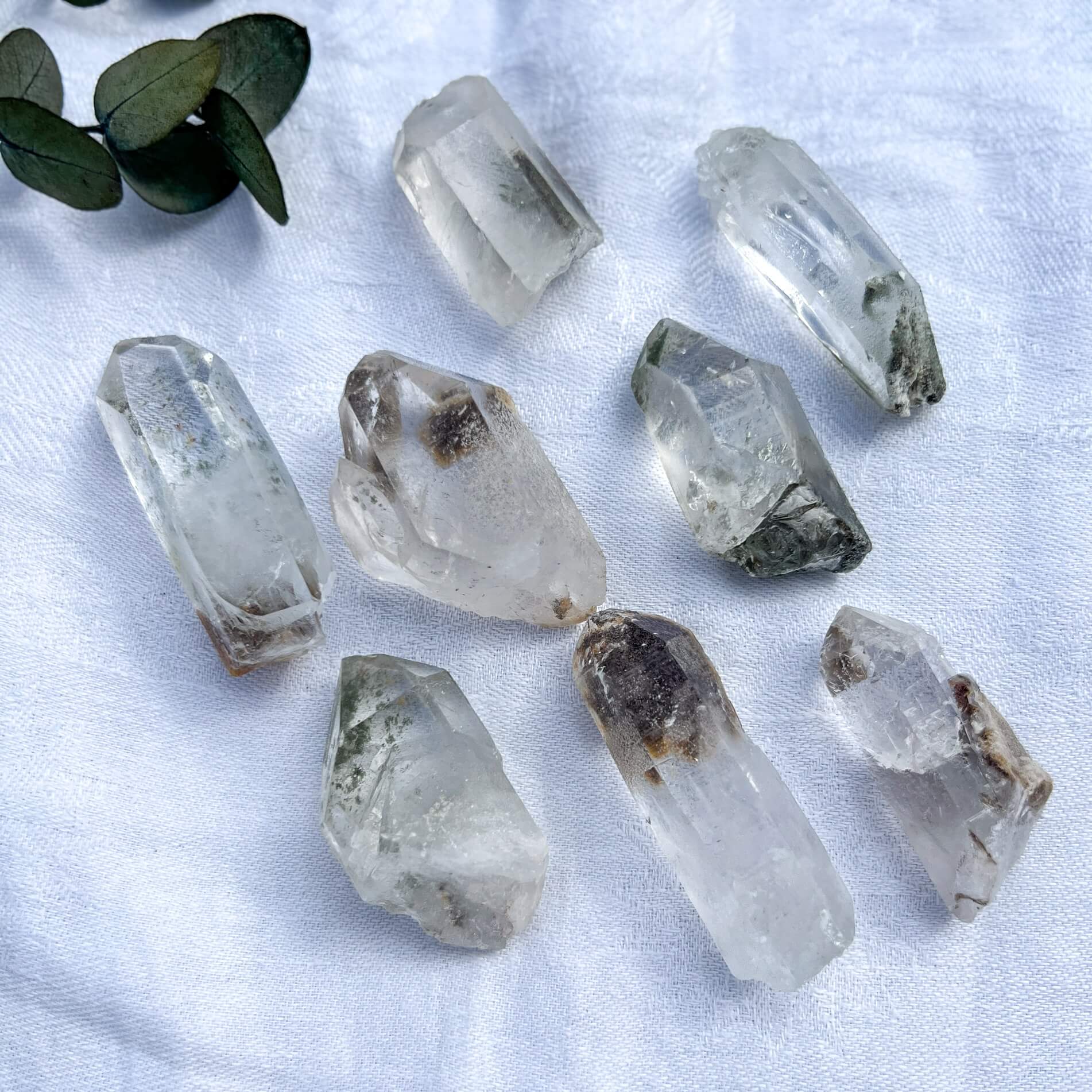 Clear shaman quartz crystals on a white fabric background