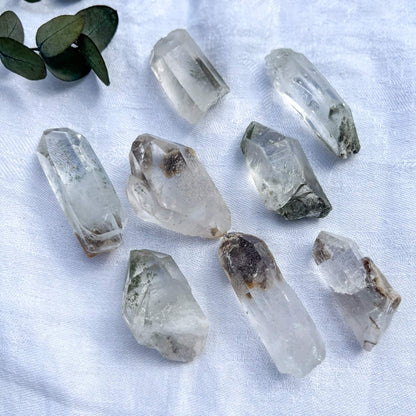 Clear shaman quartz crystals on a white fabric background