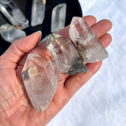 Hand holding three clear crystal rocks with a blurred background