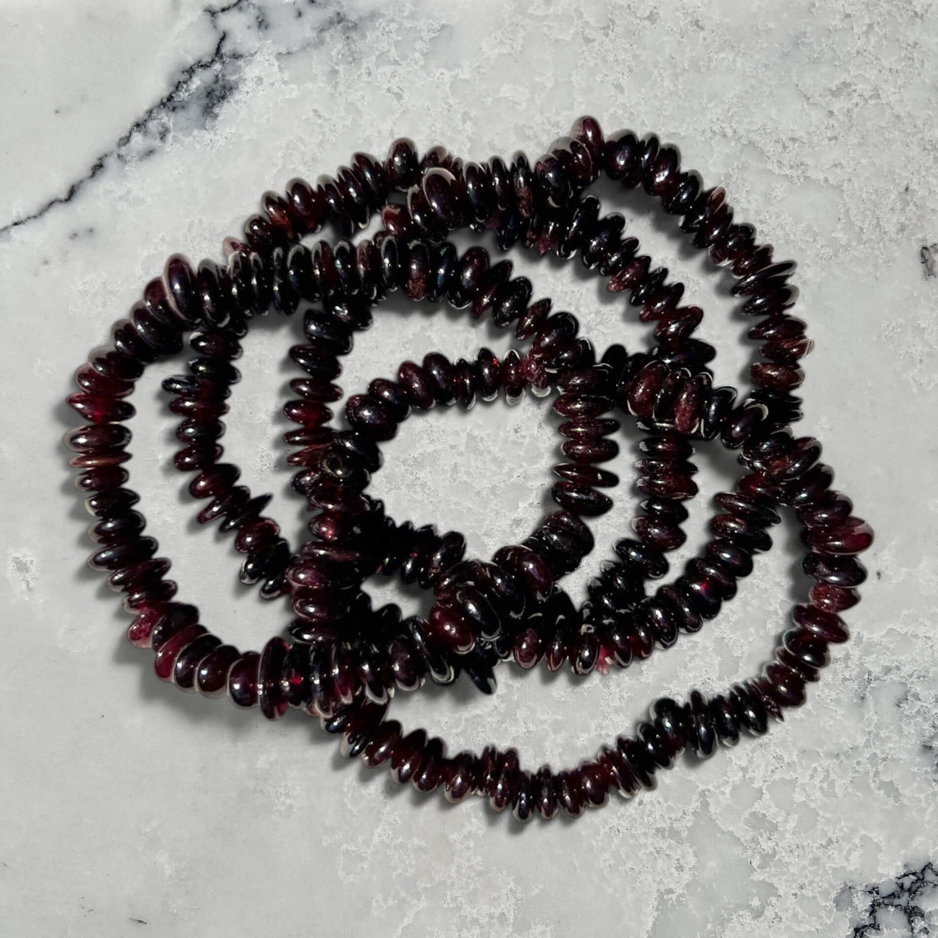 Stack of Garnet beaded bracelets on a marble surface