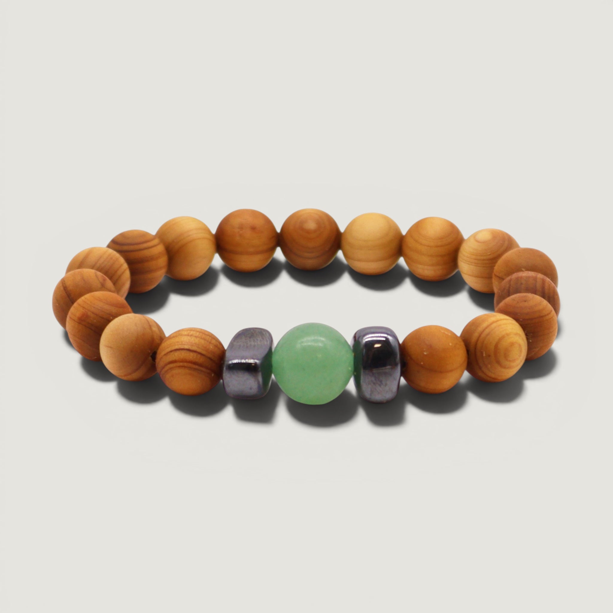 Cedar wood beaded bracelet with green aventurine and metallic black hematite beads on a plain light grey backdrop