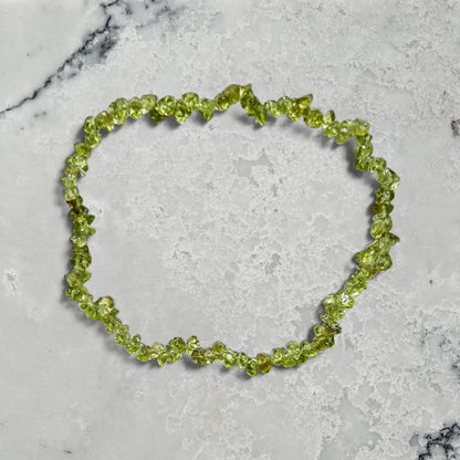 A bright green peridot crystal chip bracelet on a marble surface