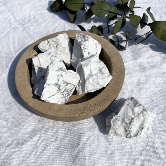 A wooden dish filled with chunky raw white and grey marbled howlite crystal pieces