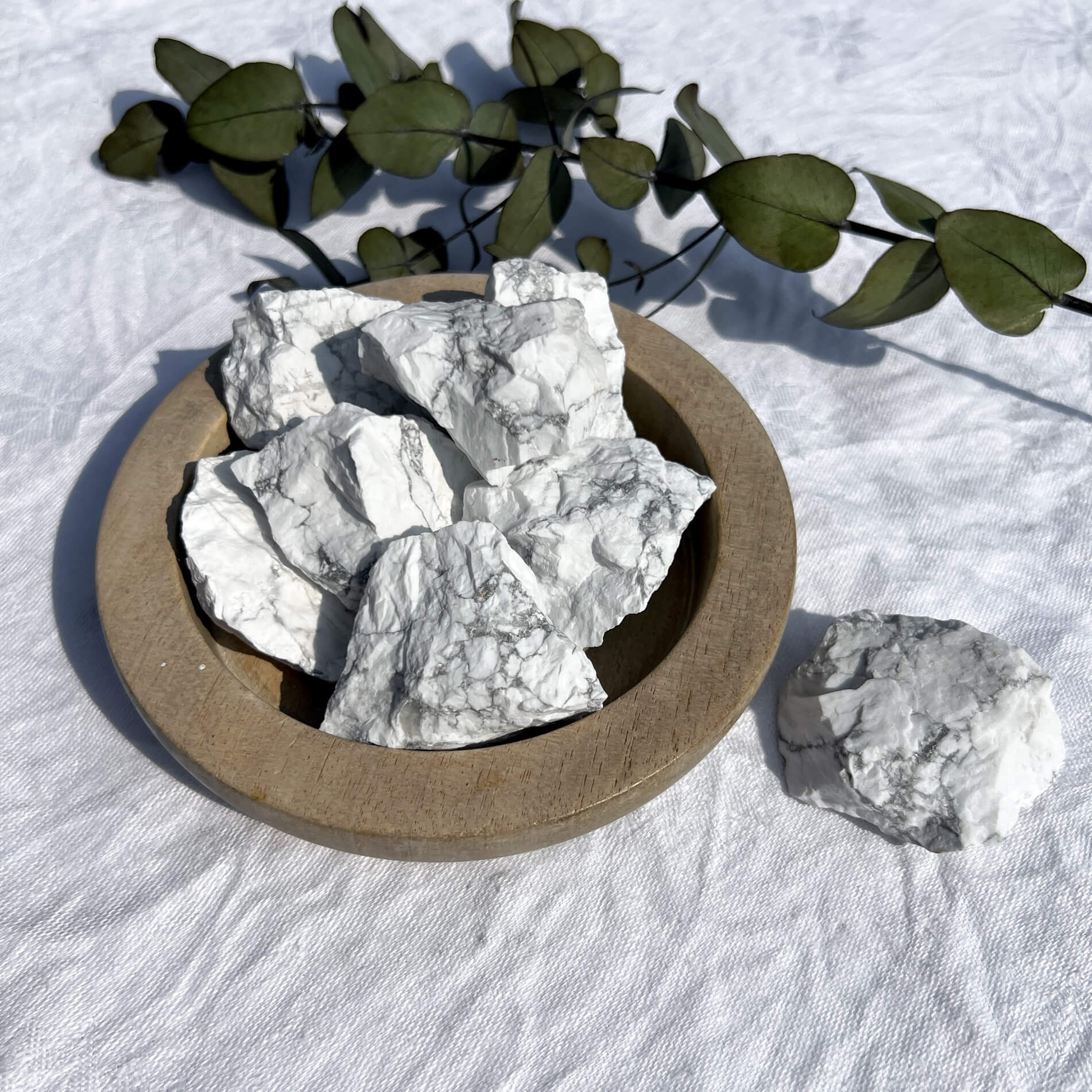 A wooden bowl filled with white and grey marbled howlite crystal chunks