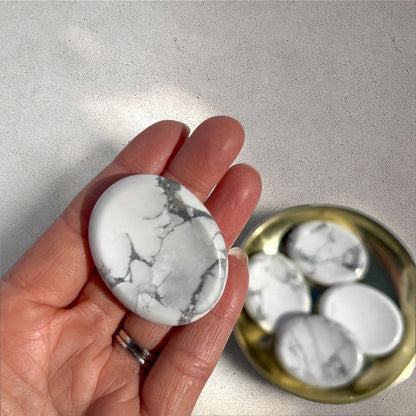 Rock + Realm Crystals polished white and grey marbled Howlite oval worry stone with thumb indentation held flat in hand.