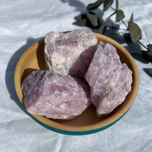 extra large lilac coloured raw kunzite crystal pieces in a wooden dish