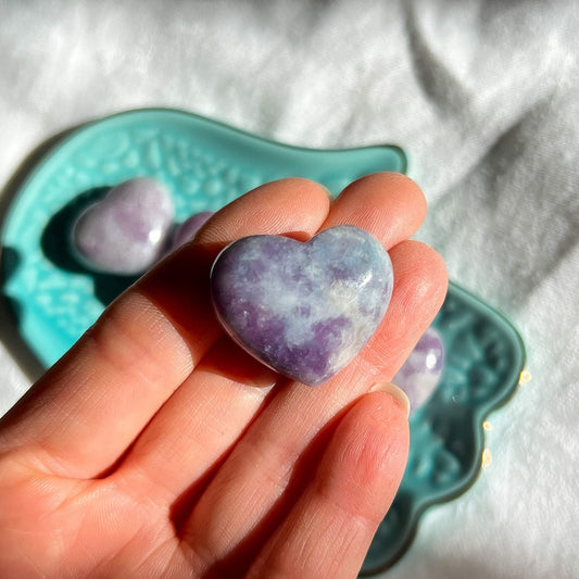 Purple and lilac coloured lepidolite crystal mini heart held in a hand