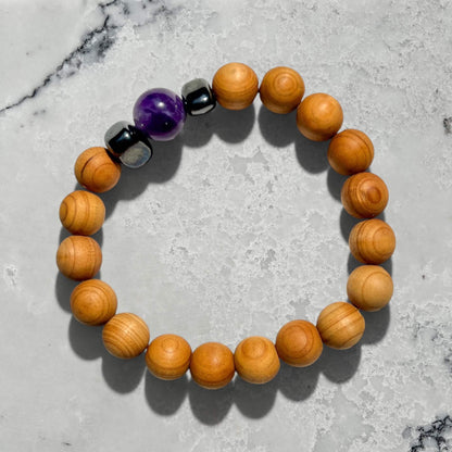 Cedar wood beaded bracelet with purple amethyst and hematite beads on a grey marble surface