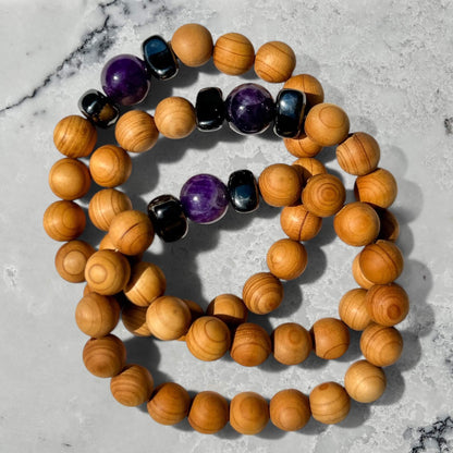 Stack of 3 cedar wood and semi-precious amethyst beads on a marble surface