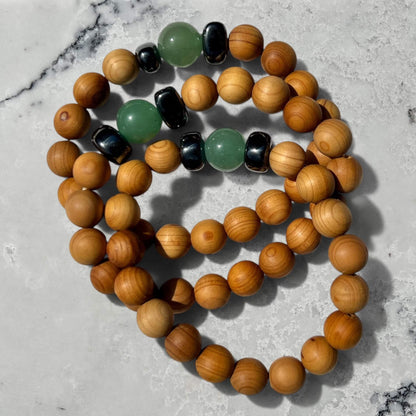 Stack of 3 Cedar wood beaded bracelets with green aventurine and metallic black hematite beads on a marble surface
