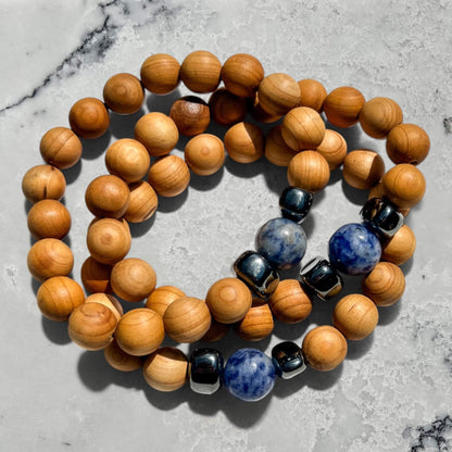 Wooden beaded bracelets with blue sodalite and hematite beads on a grey marble surface