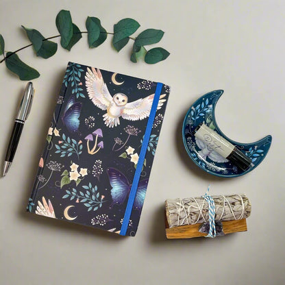 Rock + Realm Crystals dark blue journal with mystical owl, butterflies, moons, and mushrooms. Blue elastic closure.
