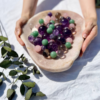 A large pink amethyst platter full of purple, green and pink crystal spheres